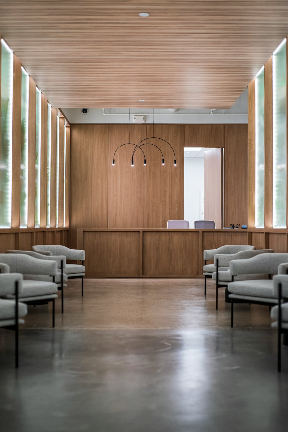 Empty waiting room with grey armchairs and reception desk.